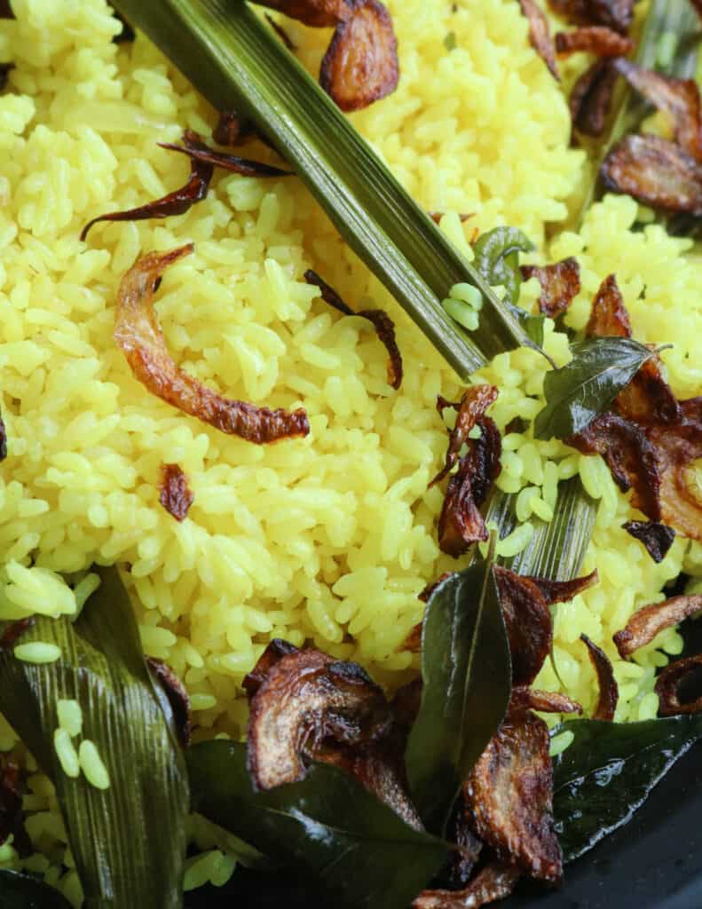 Sri Lanka yellow rice recipe garnished with fried onions, pandan leaf and curry leaves.