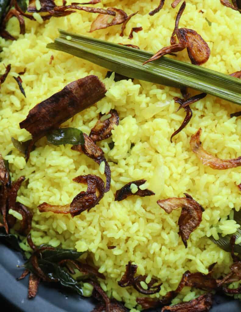 yellow rice with fried onions garnished and placed on a black platter.