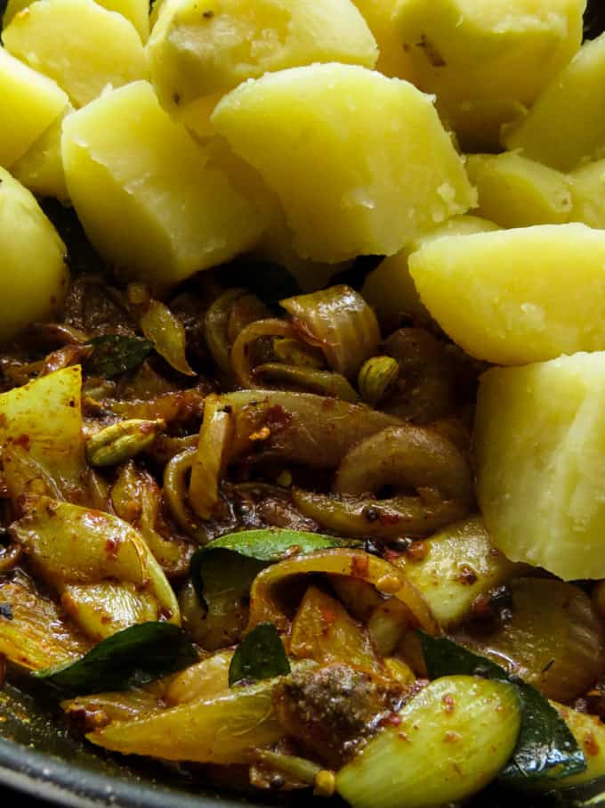 adding the boiled potatoes to the sri lankan spicy potato dish.