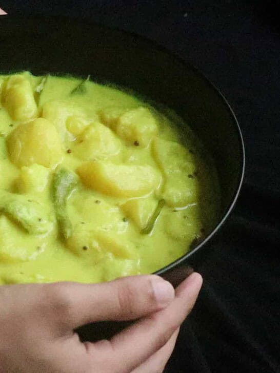 Tender potato cubes in a creamy coconut milk curry in a black bowl