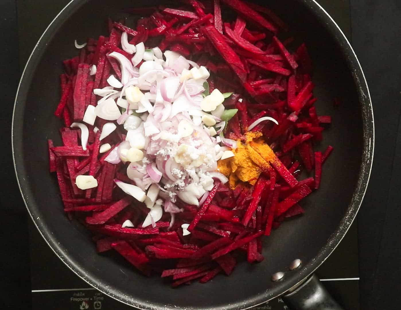 adding the beetroot strips, turmeric, and other ingredients to the pan to make the beeetroot curry.