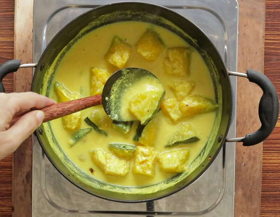 cooking the pumpkin pieces in coconut milk.