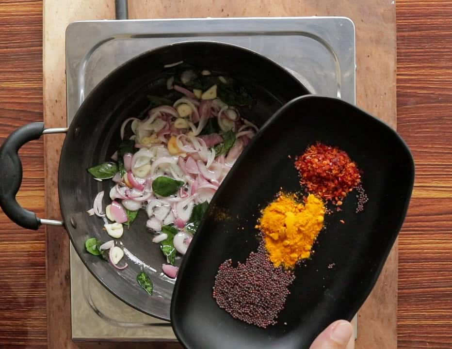 adding turmeric, red chilli flakes and mustard seeds to the frying onions, garlic and curry leaves.
