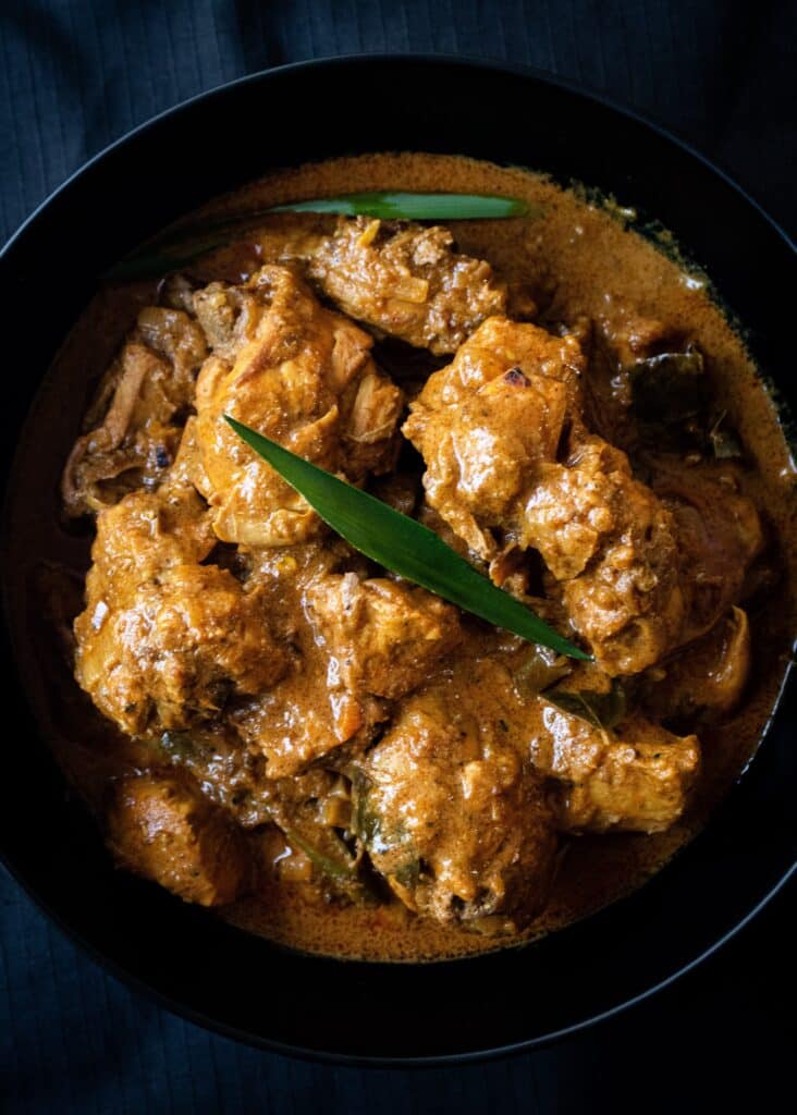 Thick Sri Lankan chicken curry placed in a bowl with pandan leaf