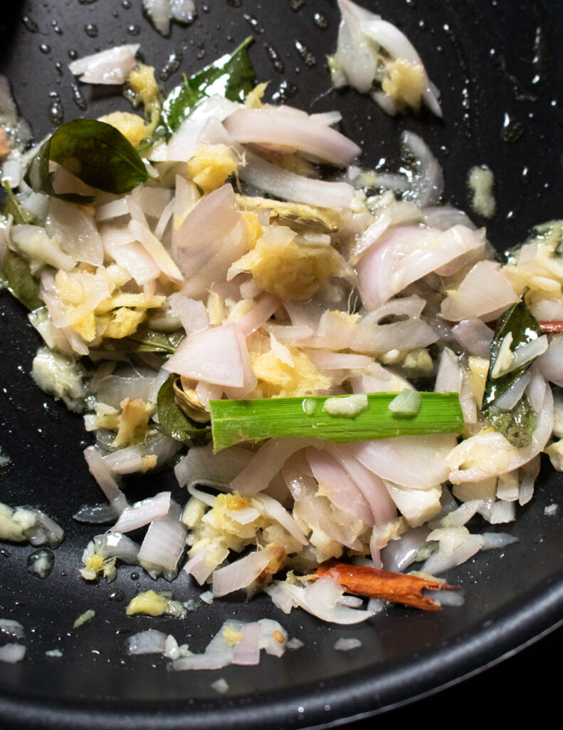 cooking the onions, pandan leaves, cinnamon, garlic and ginger to cook mutton curry