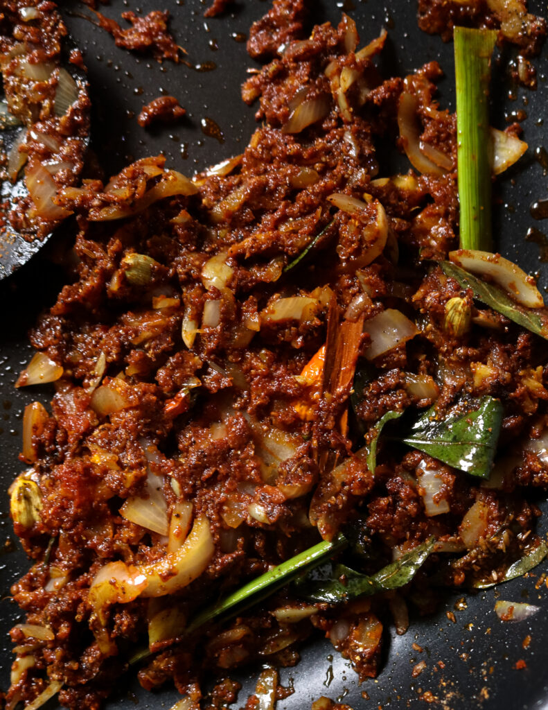 curry paste with cooked onions, curry leaves, pandan leaf and spice powders to make the mutton curry