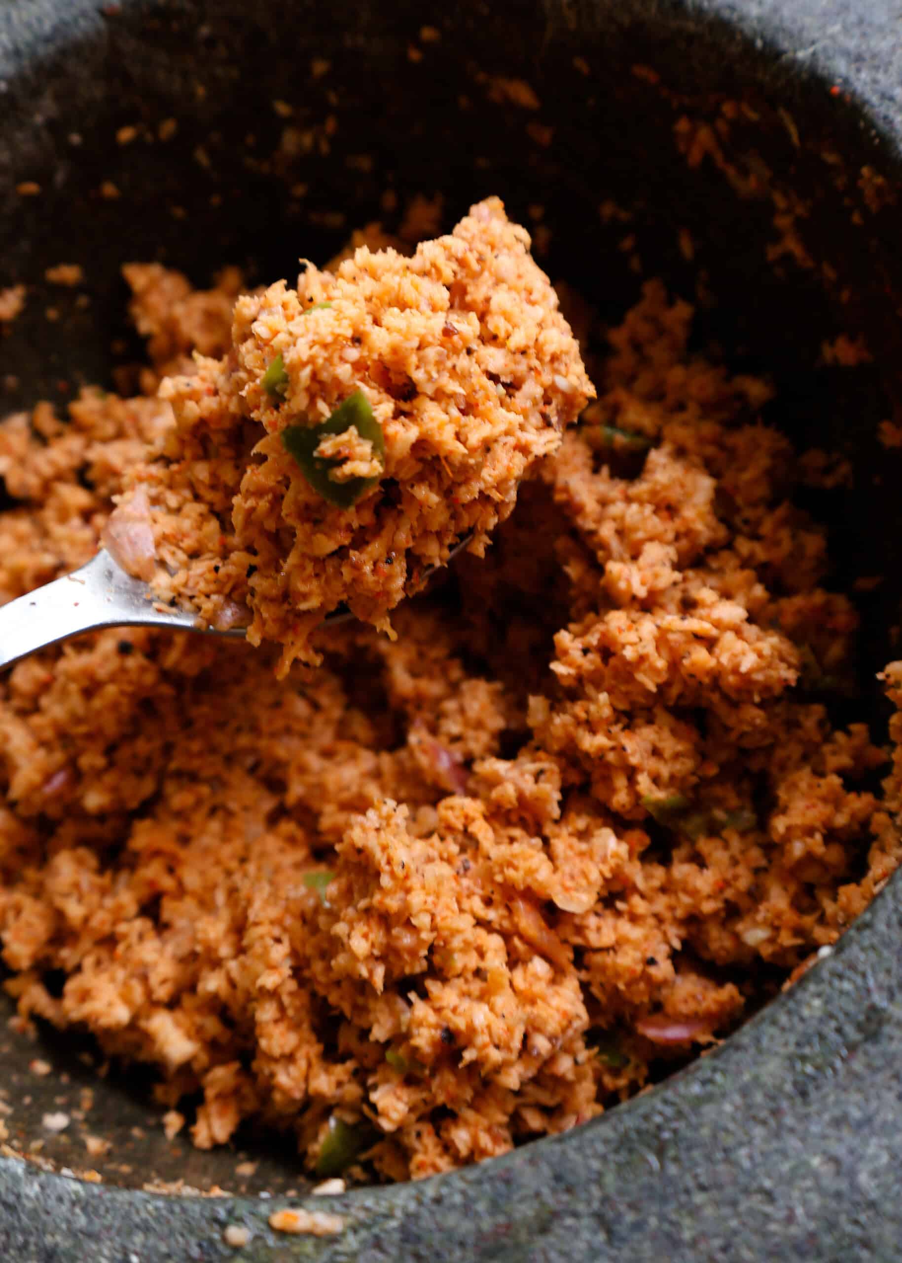 pol sambol or coconut sambol scoopedwith a spoon from a mortar and pestle.