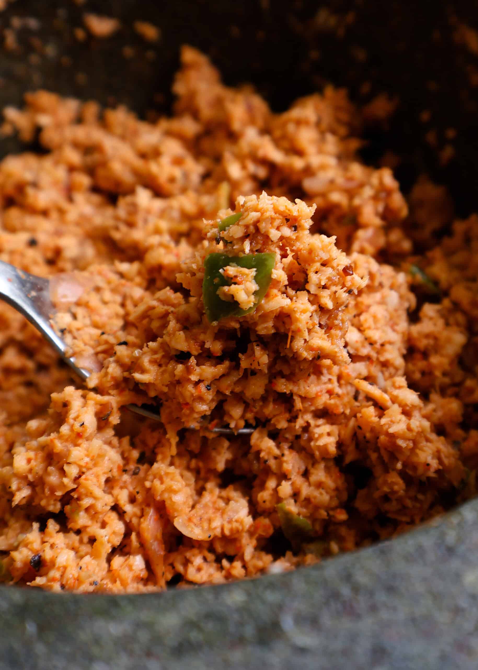 coconut sambol or pol sambol scooped with a silver spoon.