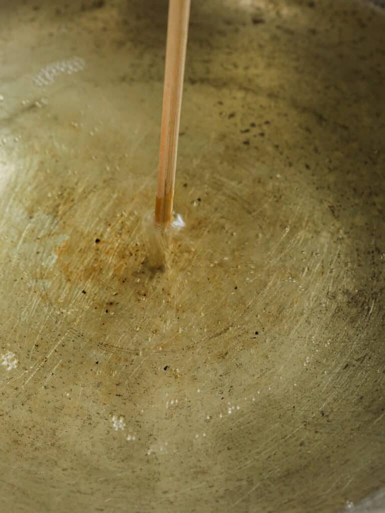 testing the oil to fry with a wooden stick to fry the hot butter cuttlefish recipe.