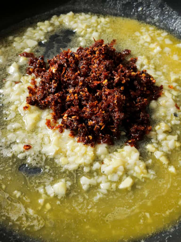 adding the chilli paste to the melting butter , minced ginger and garlic.