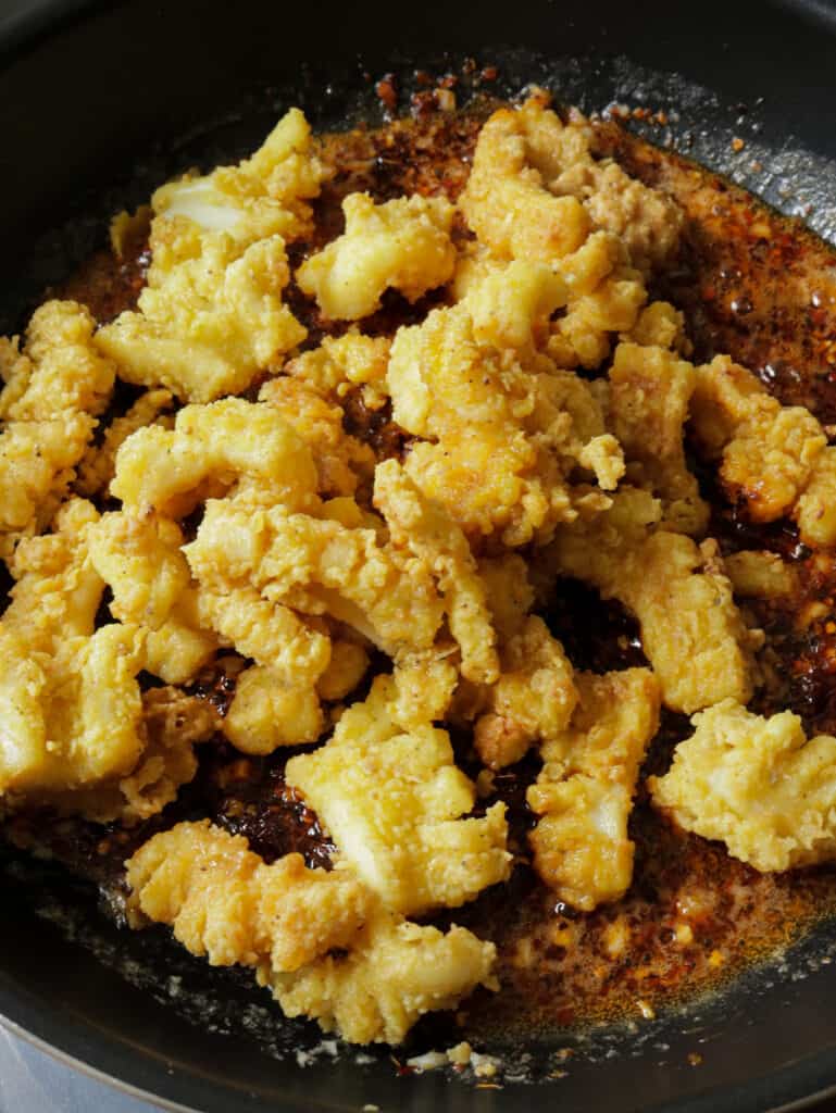 adding the cripy fried cuttlefish to the chilli paste sauce to make the hot butter cuttlefish.