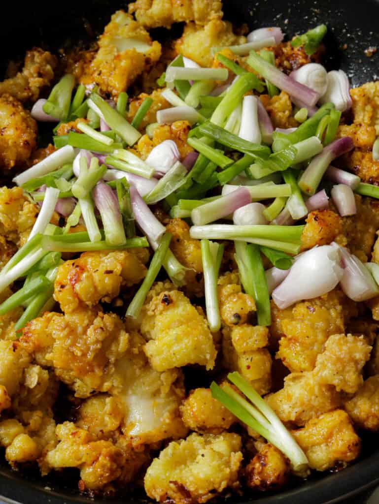 adding scallions to the fried cuttlefish.