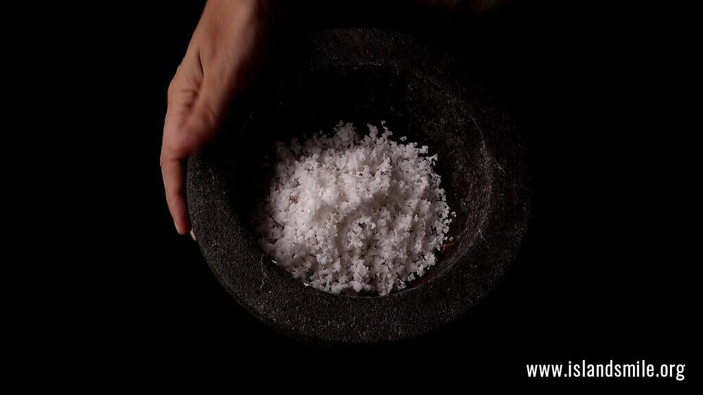 adding the scraped coconut to the mortar.