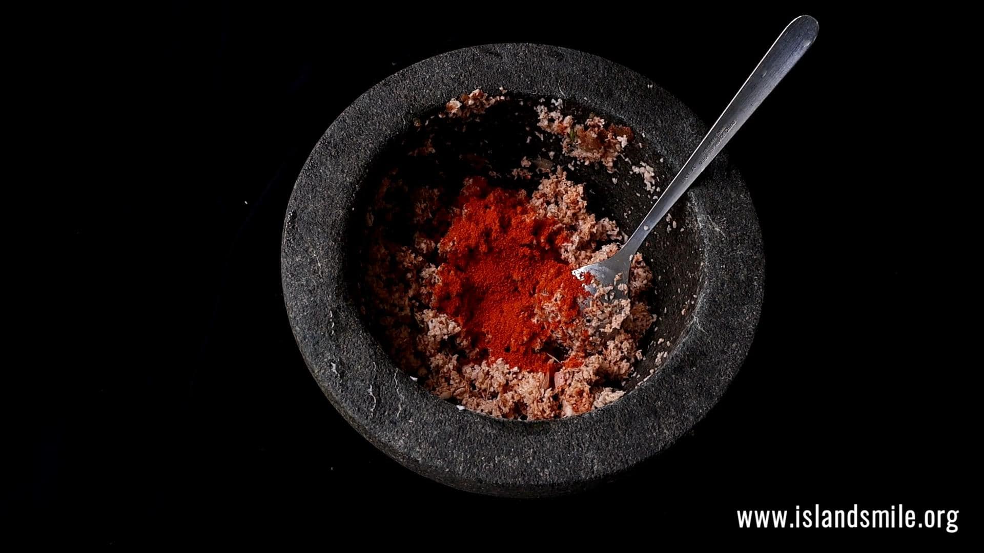 adding the rest of the red chilli powder to the coconut sambol.