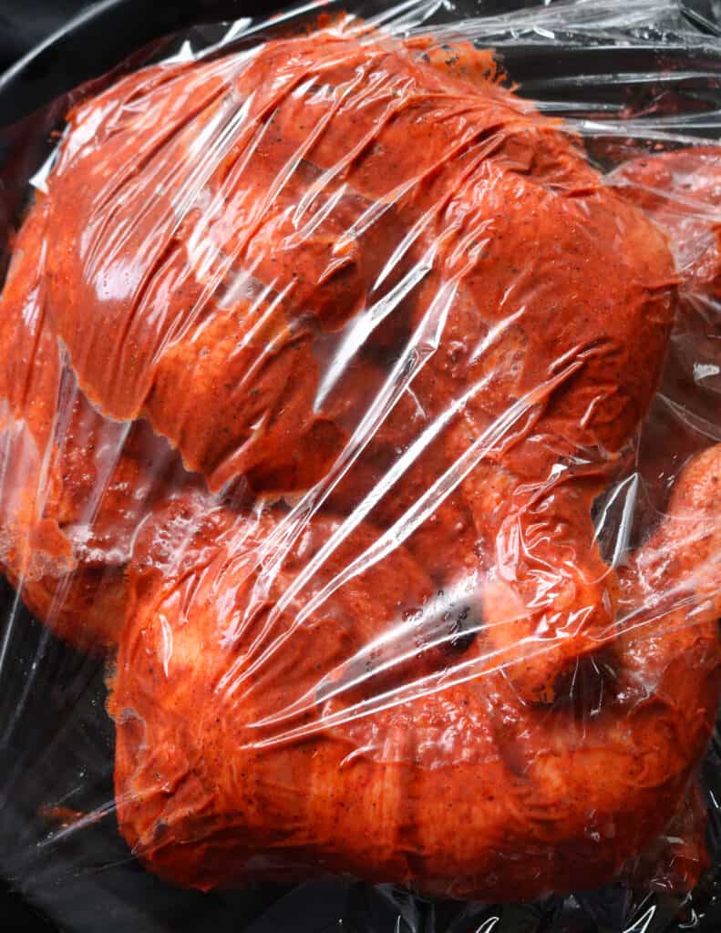 marinated tandoori chicken parts wrapped in cling to marinate and refrigerated