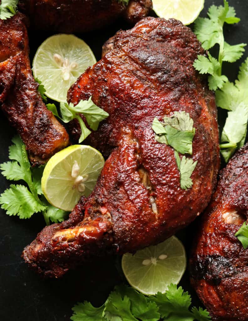 ovenbaked tandoori chicken quarters placed in a black tray,