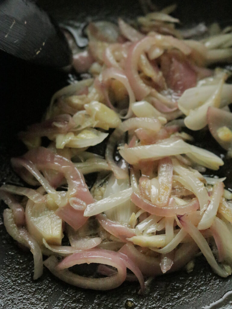 cooking the sliced onions and garlic to make the beef bone soup.