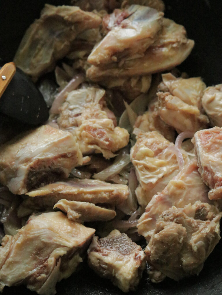 adding the beef bone to the onions to braise to cook the beef bone soup.