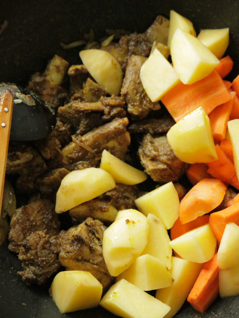 adding the fresh cubed carrots and potatoes to the braised bones to make the beef bone soup.