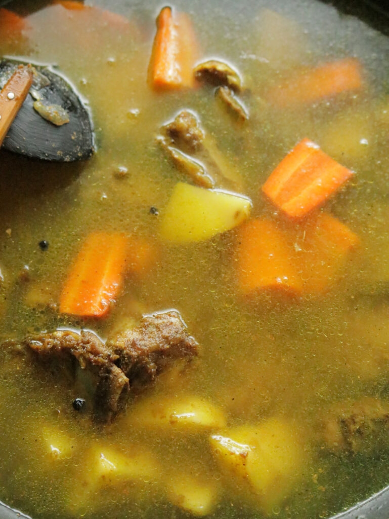 adding water to the braised beef bone and vegetables to make bone soup.