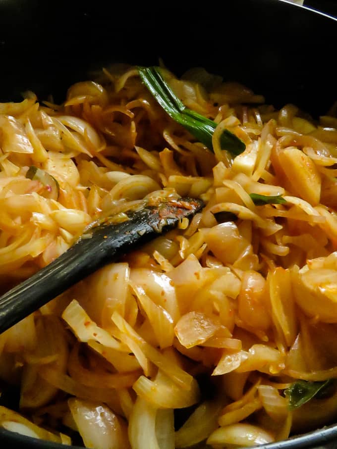 cooked onions in a pot with a spoon.