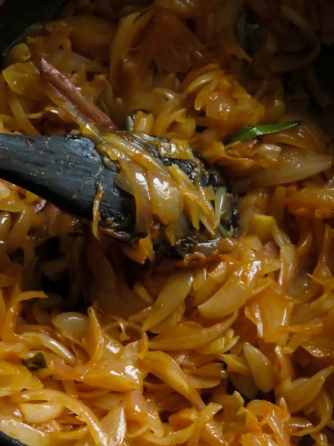 cooked onions in a pot with a spoon.