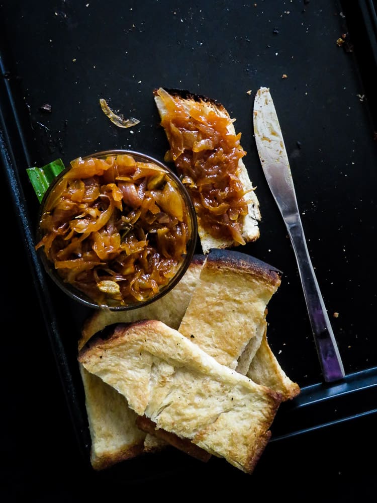 Seeni sambol in asmall bowl with a butter knife and a few slices of bread.