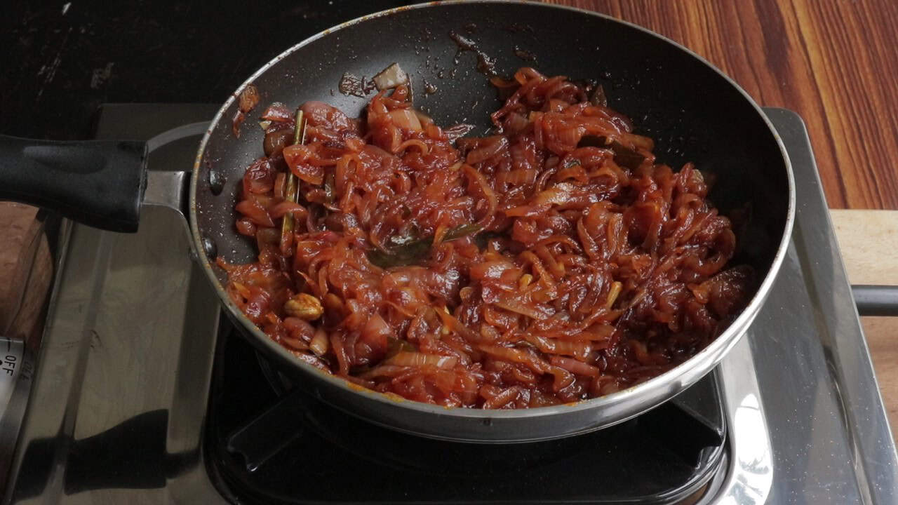seeni sambol made in a cooking pan over a stove top.