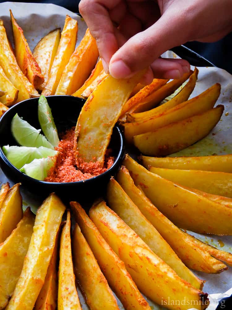 Crispy Oven-baked Potato wedges mixed with red chilli powder and turmeric.