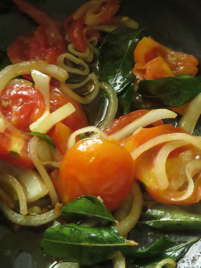 cooking onions, curry leaves, tomatoes in a pot with a few tablespoons of oil.