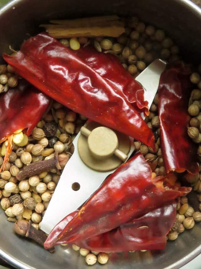 grinding the dry roasted spices into a spice grinder to make a coarse powder.