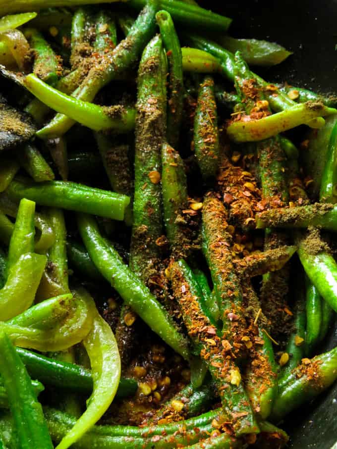 adding chiili flakes to the spicy bean fry.