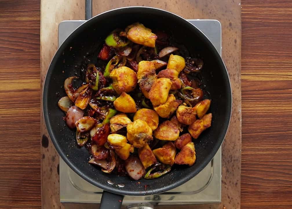 adding crispy chicken to the devilled stir fried ingredients.