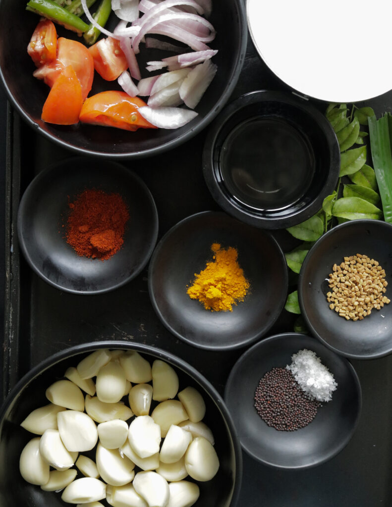 all the ingredients to make the garlic curry placed in different bowls.