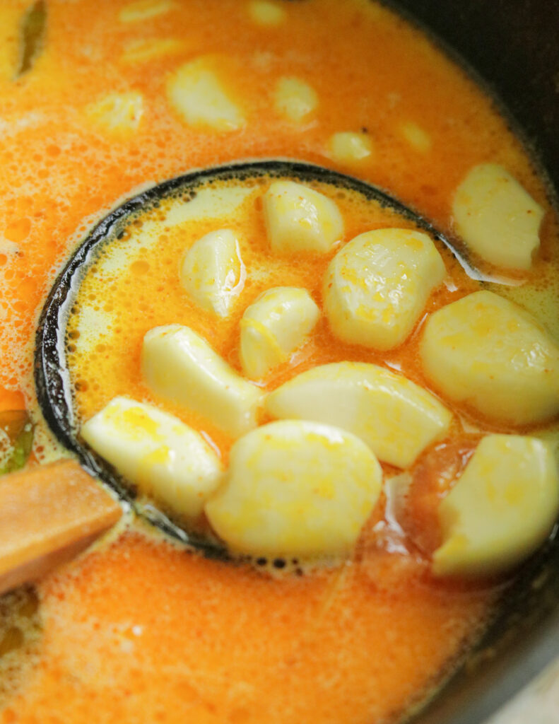 adding garlic to the coconut milk. scooped garlic in coconut gravy.