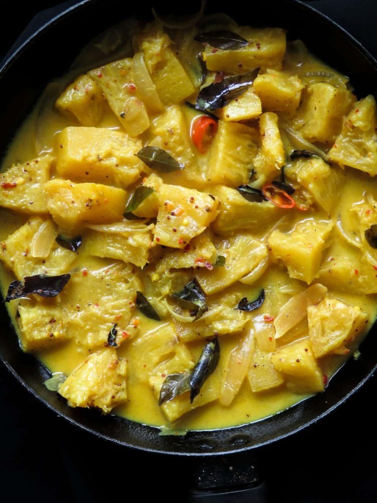 chunks of pineapple cooked in creamy coconut milk and served on a dish.