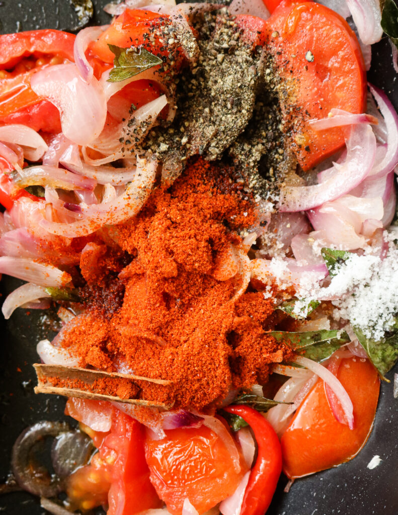 cooked tomatoes, onions, curry powder, cinnamon, red chillies,  pepper and salt in a pan.