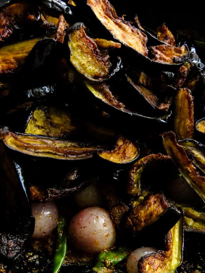 Adding fried brinjals to the pickling sauce.