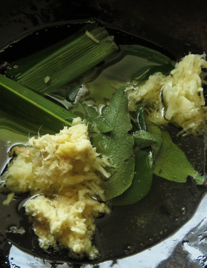 cooking pandan leaf, curry leaves, onion, ginger and garlic in oil.