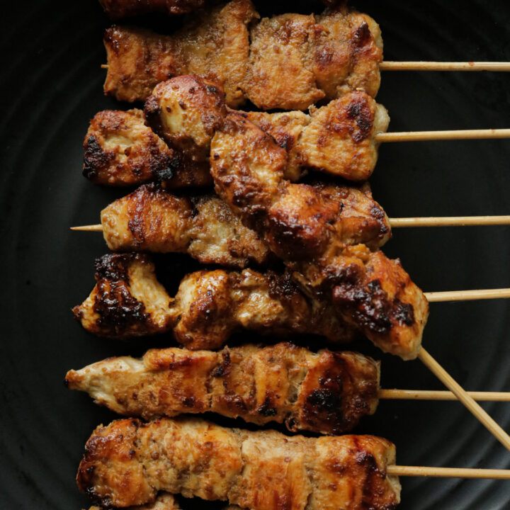 chicken satay grilled over a stove top.