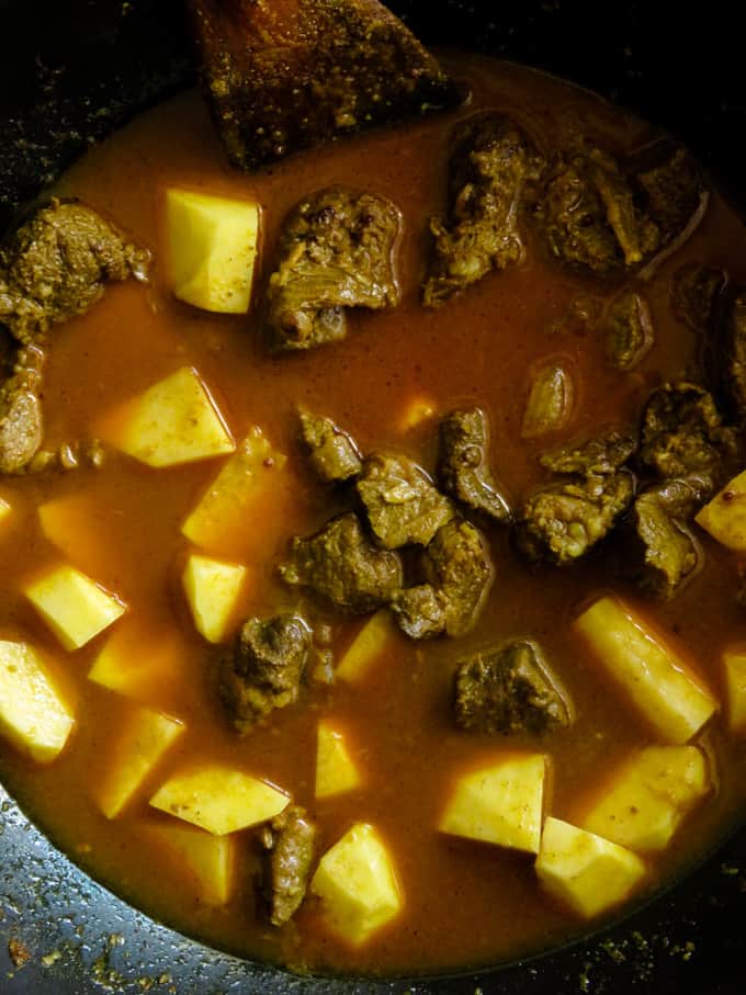 Adding potatoes to the beef to make the indian beef curry recipe.