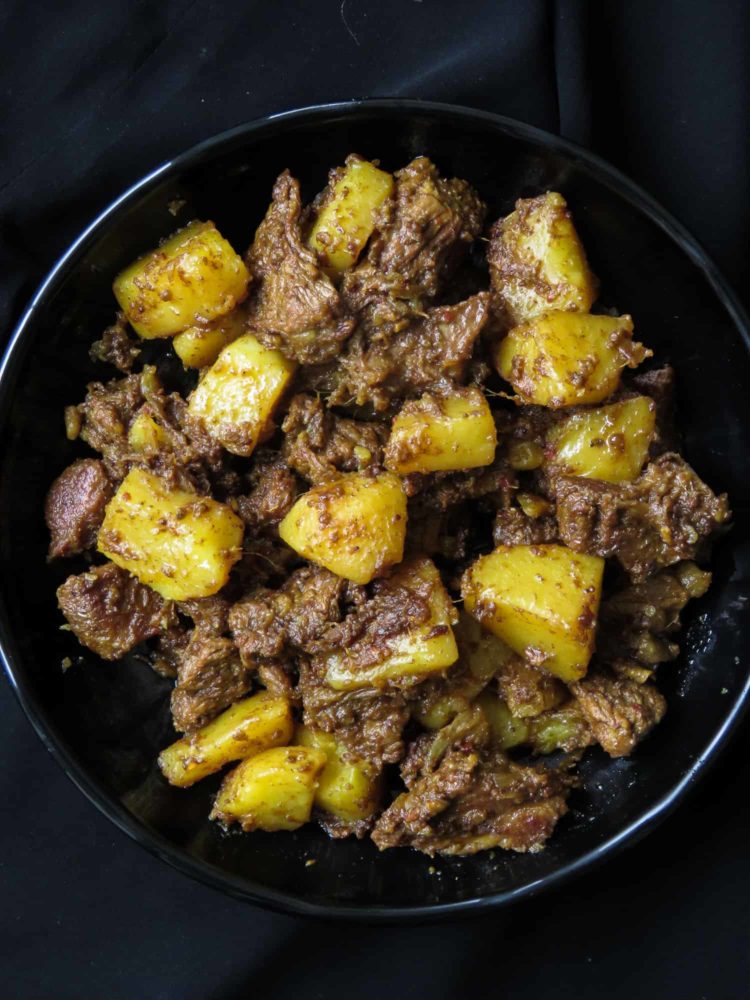 Slow cooked Indian beef and potato curry- tender meat and potatoes cooked in spices to flavor the dry gravy. this rich curry just needs a few garlic naans, roti or paratha to serve as a meal. #curry #beef #indian #meal #lunch #dinner #glutenfree #meal # potato 