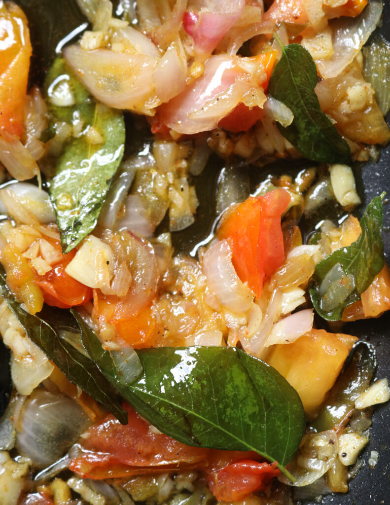 tempering onions, garlic, curry leaves, tomatoes with oil