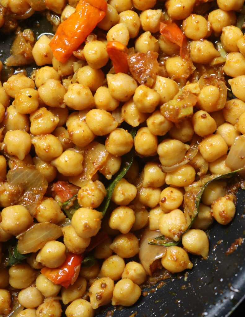 cooking the chickoeas with onions, curry leaves and spices in oil