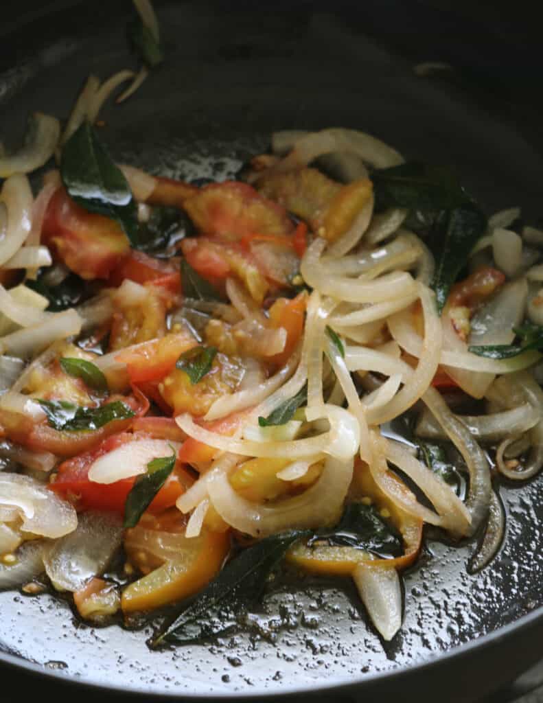 cooking the onions, tomatoes and curry leaves to make the chettinad chicken.