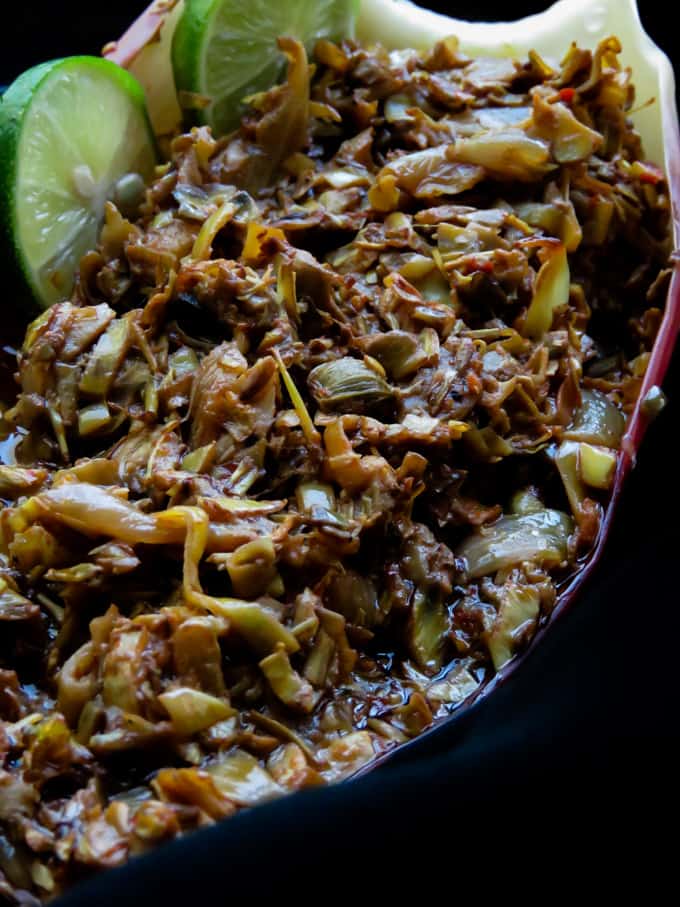 banana flower curry in a banana leaf with wedges of lime.