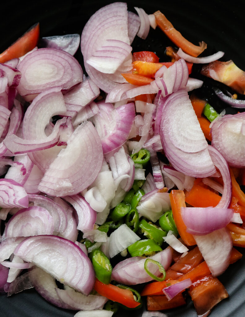 mixing onions, green chillies and sliced tomatoes to make the salad
