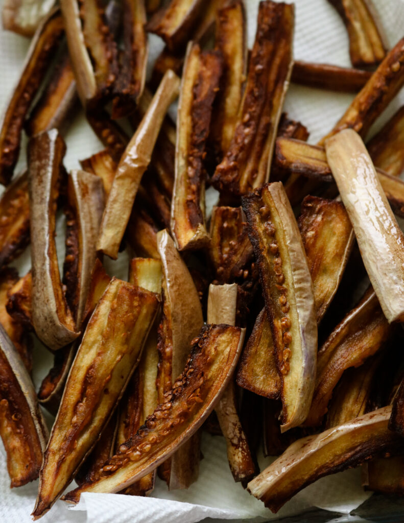 fried eggplant striips placed in kitchen paper towels to soak oil