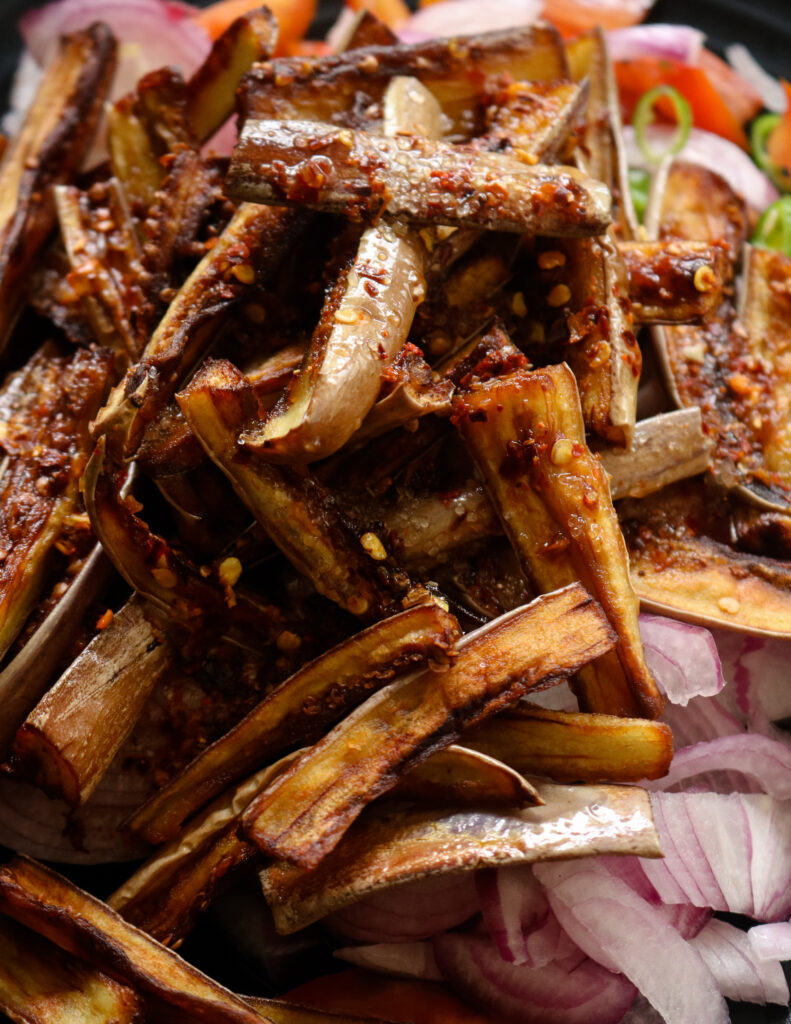 pouring the vinaigrette over the fried eggplant and onions