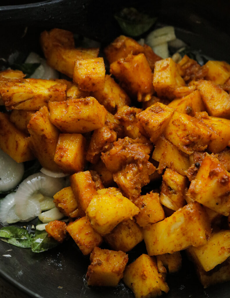 marinated pineapple added to the tempering onions, curry leaves, garlic to make the pineapple curry.